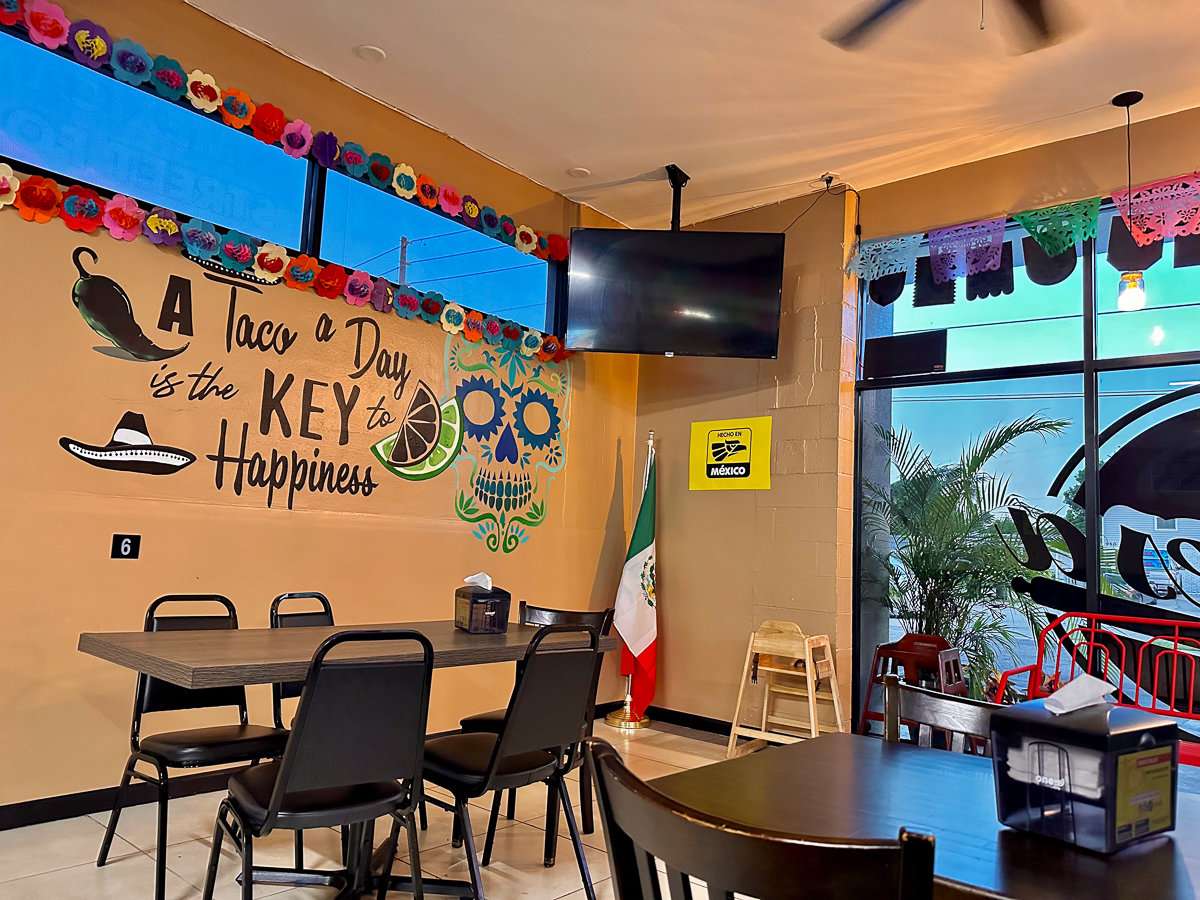 corner of restaurant with chairs and taco mural 